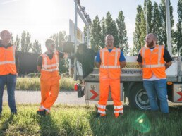 Medewerkers van Versluys Verkeerstechniek staan samen bij een werkvoertuig langs de weg tijdens werkzaamheden in de infrastructuur.