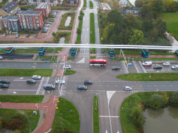 Luchtfoto van een druk kruispunt met verkeersstromen, fietspaden en openbaar vervoer als onderdeel van een verkeersplan van Versluys Verkeerstechniek.