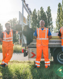 Vier medewerkers van Versluys Verkeerstechniek in oranje veiligheidshesjes bij een bedrijfswagen met mobiele verkeerssignalering