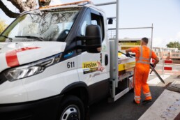 Medewerker van Versluys laadt tijdelijke verkeersborden in een werkbus voor plaatsing op locatie.