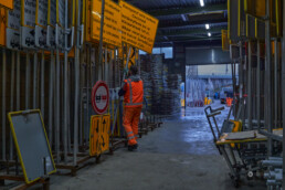 Werfmedewerker in het magazijn van Versluys Verkeerstechniek tussen rekken met verkeersborden en afzetmateriaal