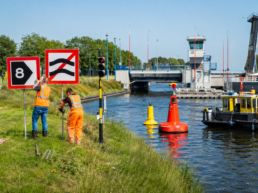 Tijdelijke vaarwegmarkering, betonning en scheepvaartborden bij werkzaamheden aan een brug en sluis.