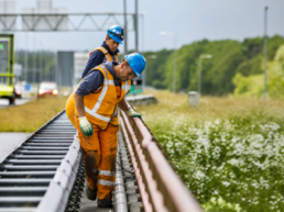 Twee wegwerkers inspecteren een geleiderail langs een afgezette rijbaan.